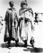 Dva stojící muži – Tuareg nižší kasty s bílým závojem a Afričan