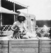 B.Machulka sedí se zvířaty (psík a hyenka) na bedně na dvoře svého domu v Chartúmu